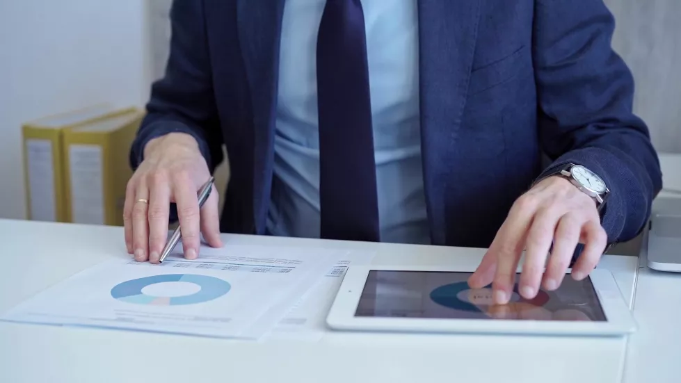 businessman-with-blue-suit-is-analyzing-financial-data-using-charts-graphs-paper-tablet
