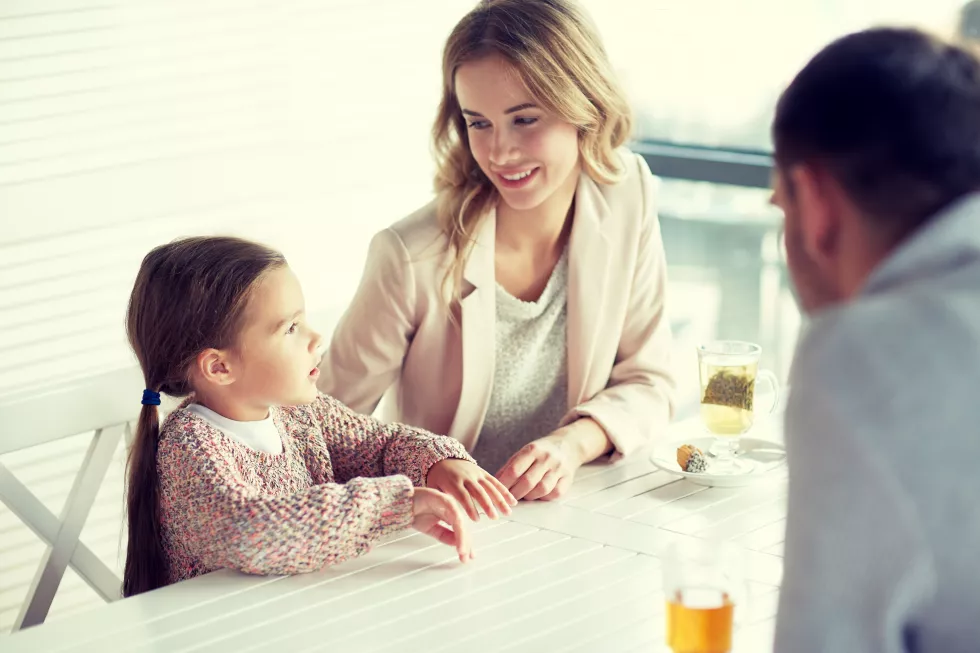family-parenthood-communication-people-concept-happy-mother-father-little-girl-having-dinner-talking-restaurant-cafe