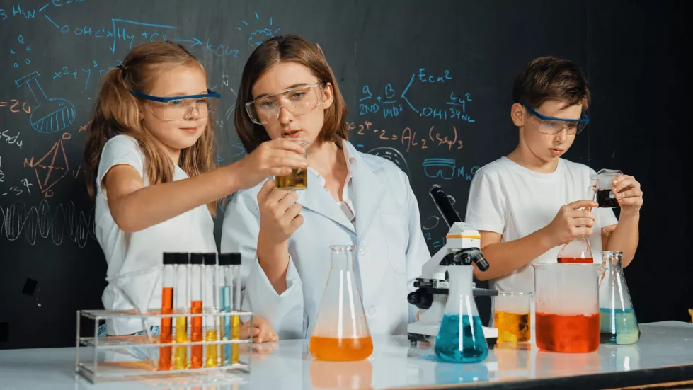 caucasian-boy-mixing-chemical-liquid-while-teacher-giving-advice-erudition