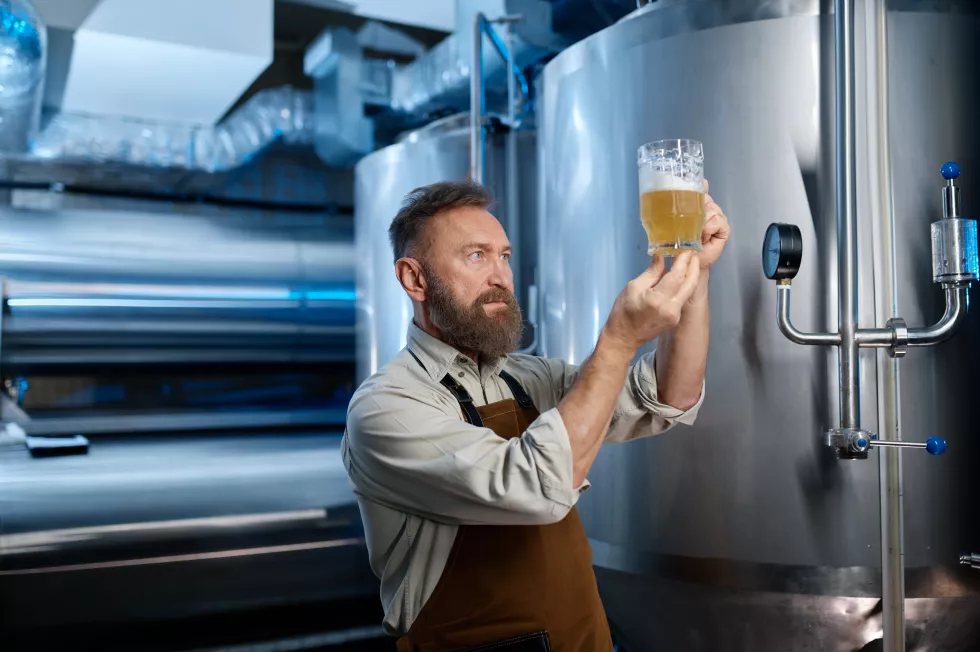 brewery-worker-looking-freshly-made-beer-glass-mug-brewing-factory-technological-process-concept