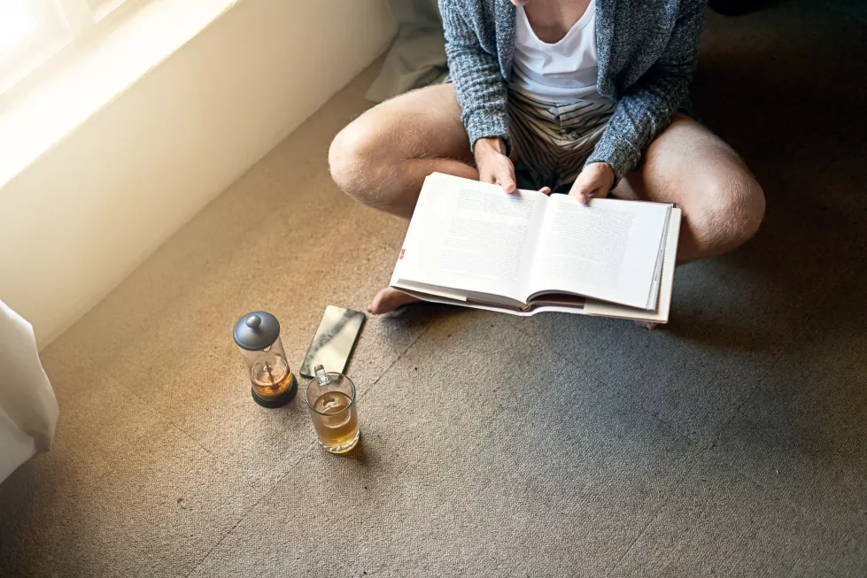 relax-man-reading-book-floor-knowledge-entertainment-story-living-room-lens-flare-high-angle-person-with-cup-tea-information-hobby-studying-literature-home