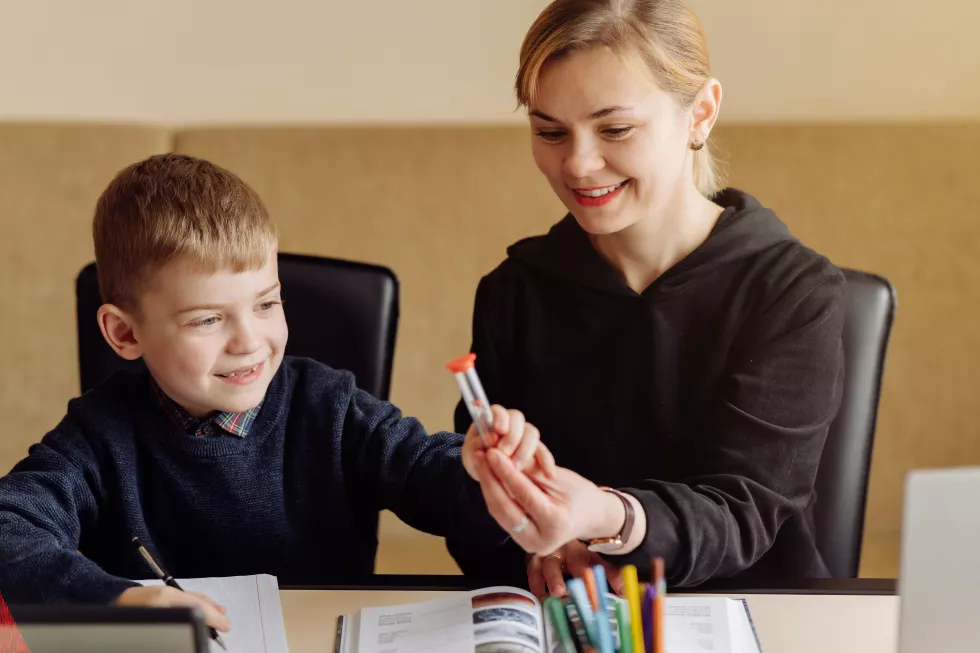 mother-using-laptop-tablet-teaching-with-her-son-online-home-his-room