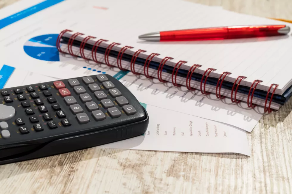 close-up-documents-with-spiral-notebook-pen-by-calculator-table