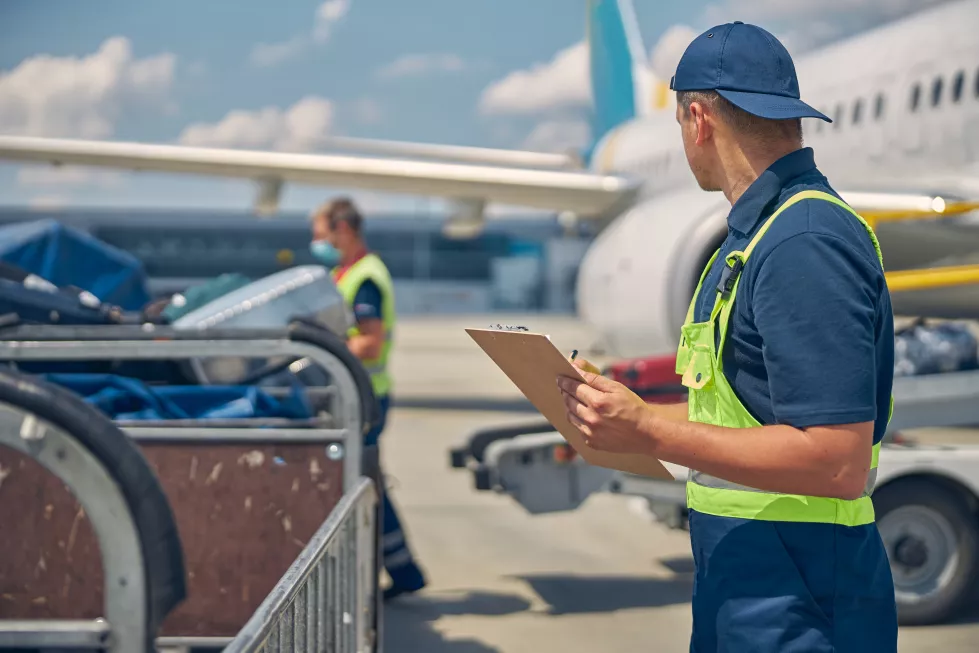 back-view-caucasian-male-worker-monitoring-luggage-uploading-onto-conveyor-belt