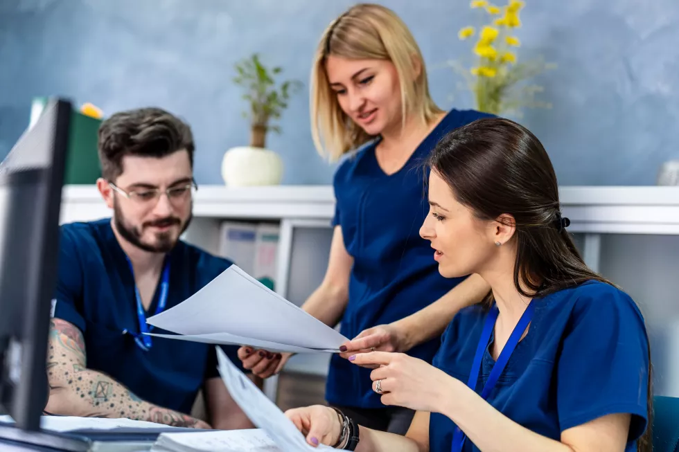 smiling-group-diverse-doctors-reading-patient-s-notes-together-while-standing-office-hospital