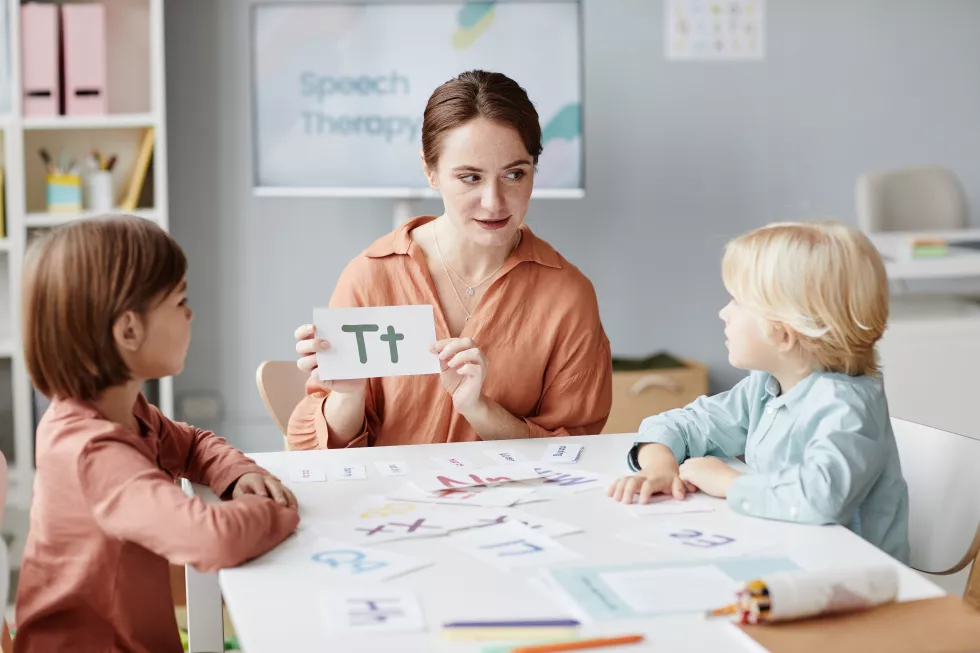 young-english-teacher-showing-card-with-letter-children-they-learning-it-table-lesson