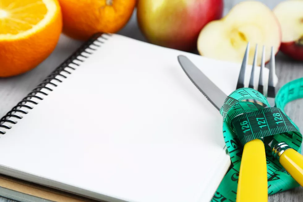 cutlery-tied-with-measuring-tape-notebook-with-fruits-wooden-background