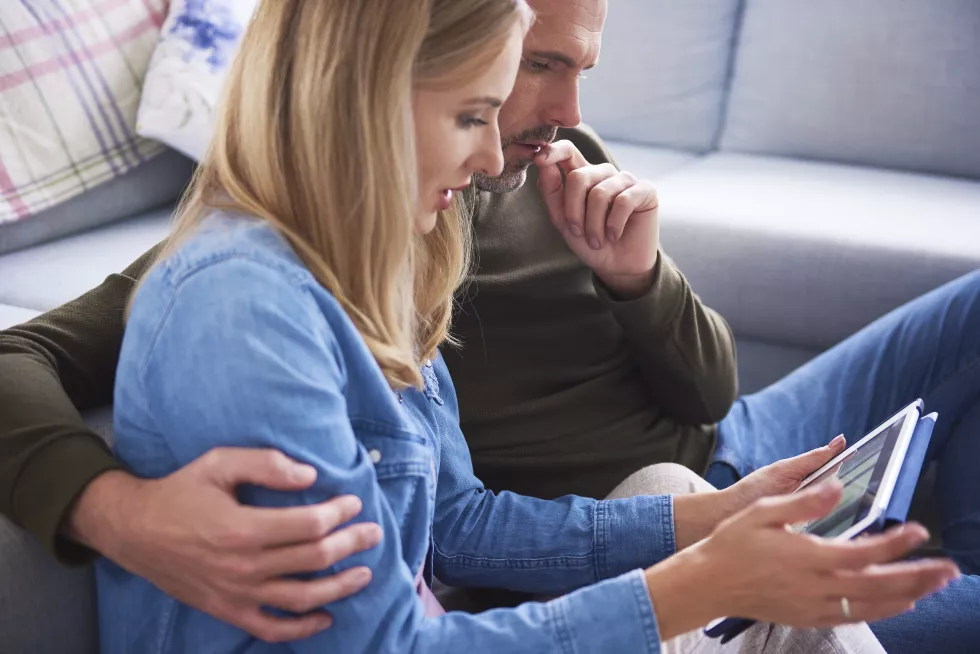 couple-using-digital-tablet-while-sitting-home