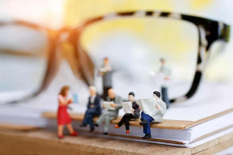 miniature-businessman-sitting-books
