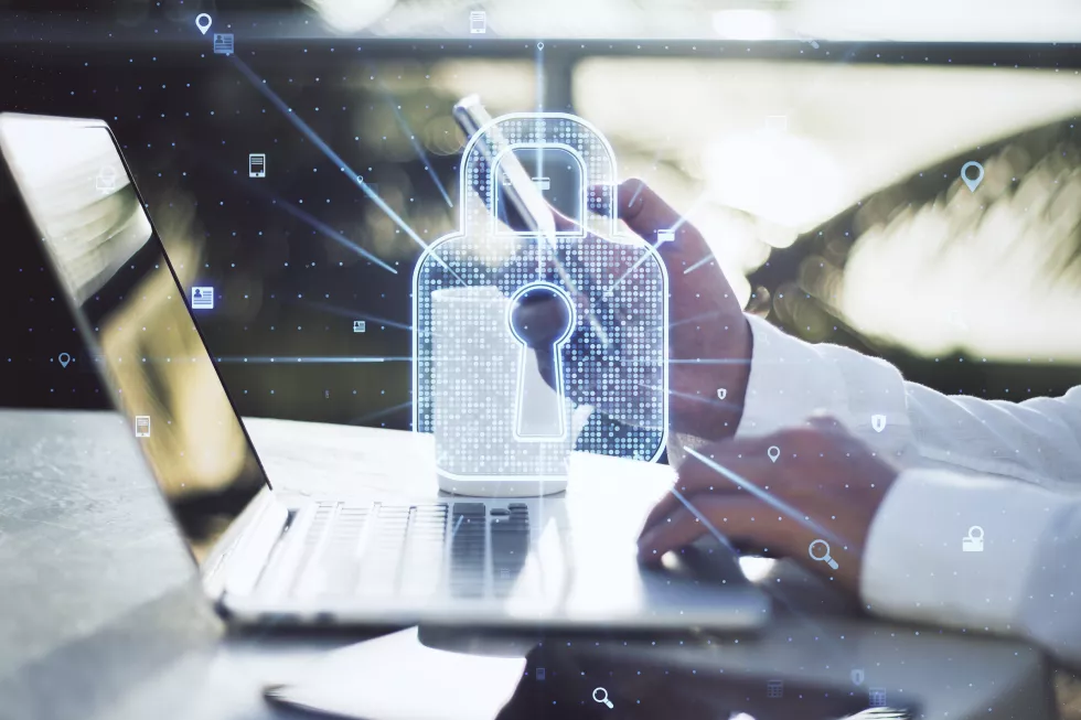 close-up-businessman-hand-using-laptop-smartphone-with-creative-glowing-web-security-padlock-blurry-background-secure-information-concept-double-exposure