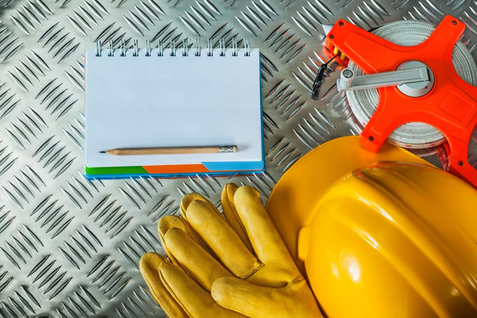 protective-gloves-building-helmet-measuring-tape-notebook-pencil-fluted-metal-sheet