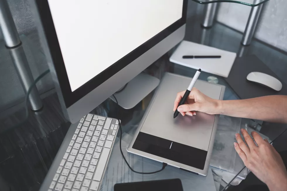 workplace-photographer-graphic-designer-creative-designer-hands-working-laptop-with-graphic-tablet-computer-monitor-keyboard-empty-notebook-mouse-smartphone