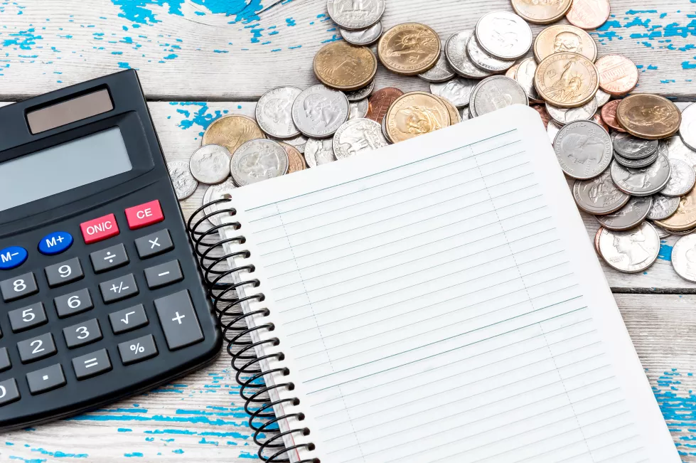 notepad-with-calculator-coins-wooden-table-business-concept