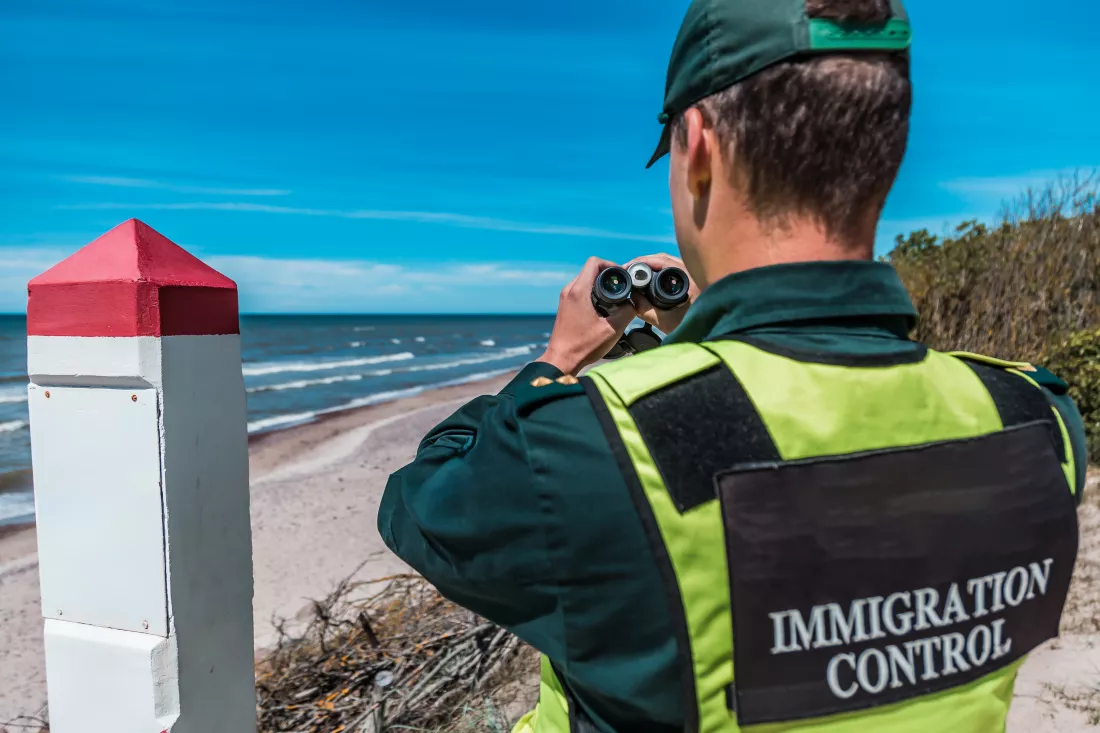 immigration-control-officer-surveying-coast-with-binoculars-vigilant-national-border-protection-duties-sunny-day