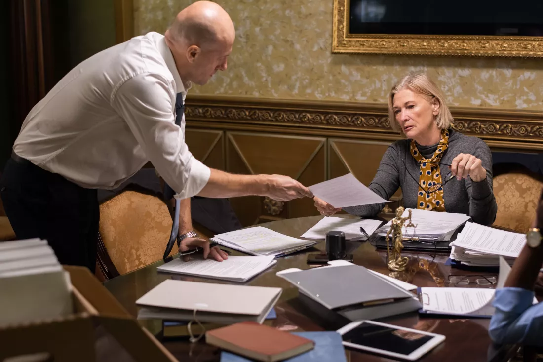 bald-businessman-passing-paper-his-mature-female-colleague