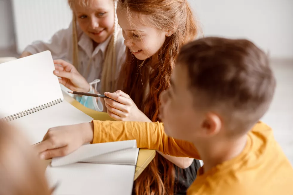 happy-children-sitting-table-using-notebooks