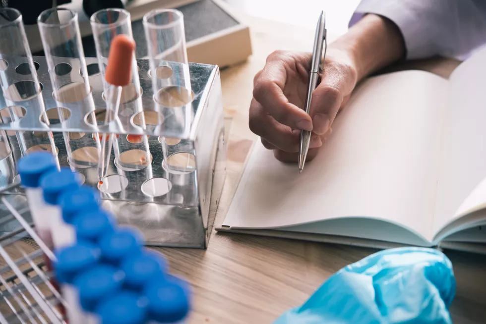 cropped-hand-scientist-writing-book-desk