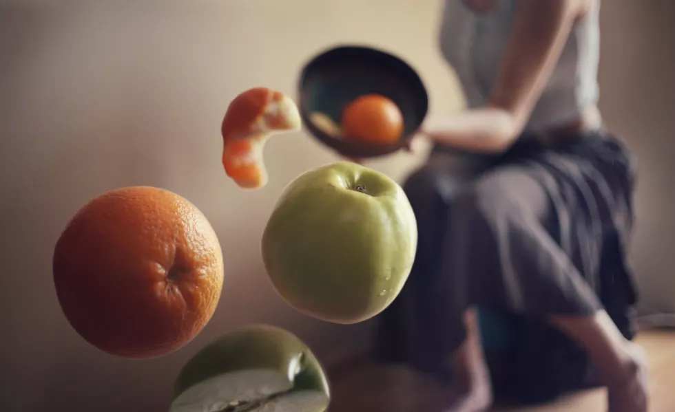 midsection-woman-throwing-fruits-bowl-home