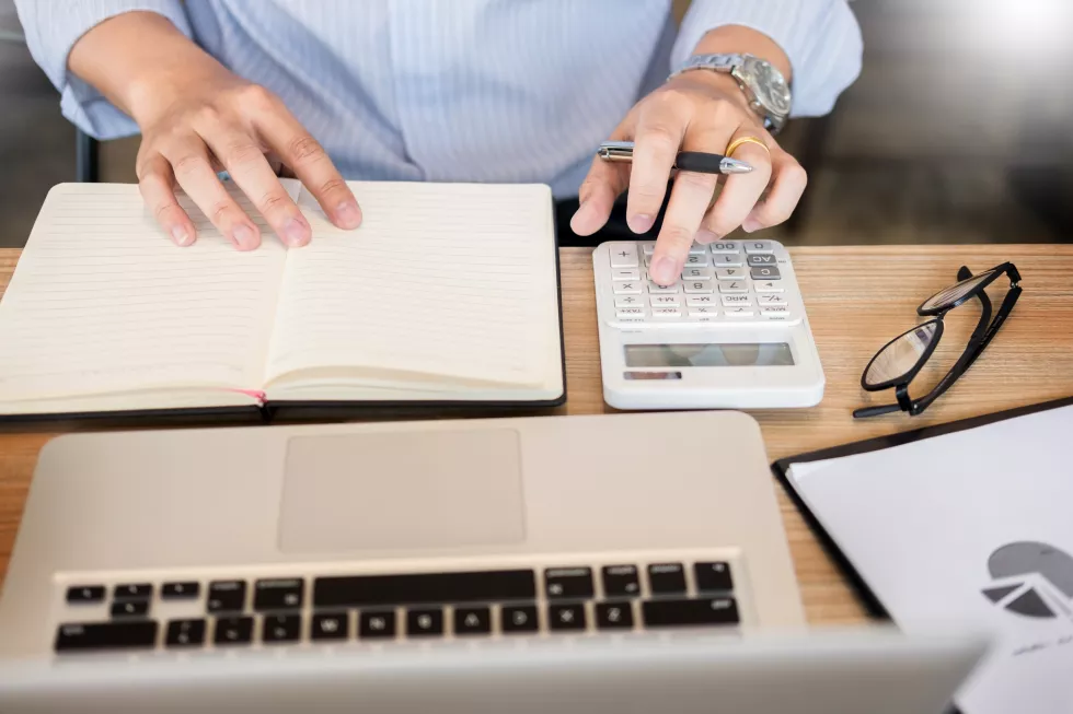midsection-businessman-using-calculator-while-sitting-desk