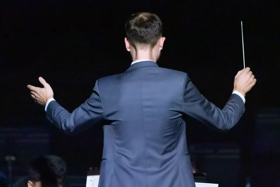 rear-view-well-dressed-musical-conductor-gesturing