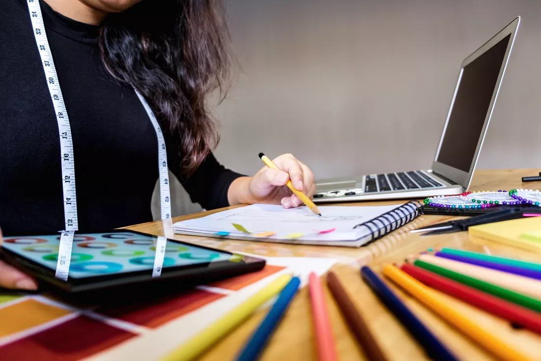midsection-fashion-designer-making-sketch-desk-studio