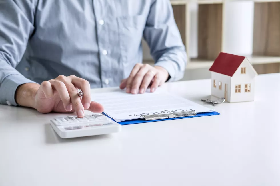 midsection-real-estate-agent-with-reading-contract-papers-desk-office