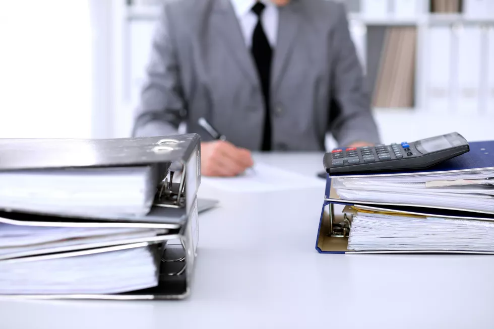 binders-with-papers-are-waiting-be-processed-with-business-woman-back-blur-accounting-planning-budget-audit-insurance-concept