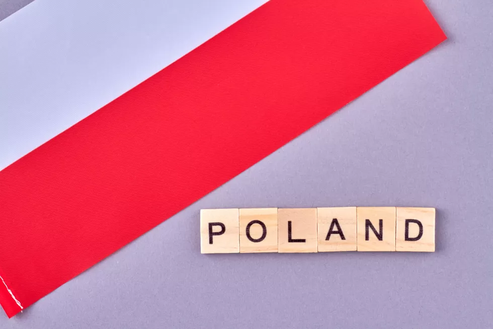 poland-written-with-wooden-blocks-national-flag-european-country-isolated-violet-background