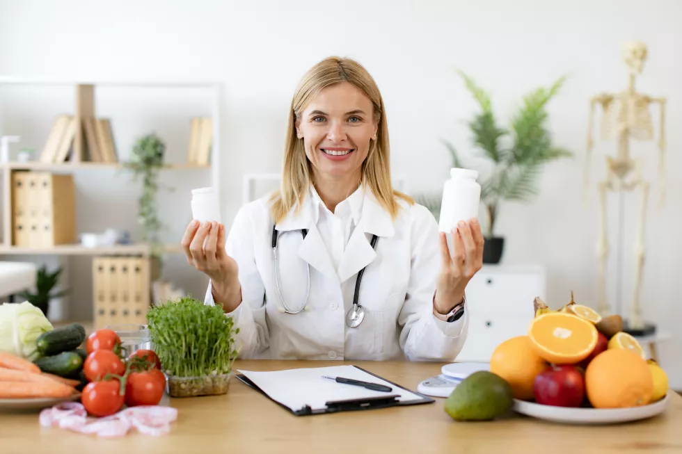 caucasian-lady-lab-coat-smiling-camera-while-demonstrating-pills-bottles