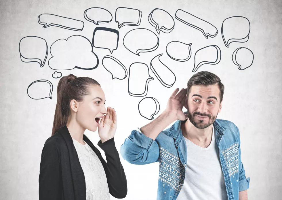 smiling-young-man-casual-clothes-listening-attentively-with-his-hand-near-ear-young-woman-shouting-with-hand-near-mouth-concrete-wall-background-with-speech-bubbles-mock-up