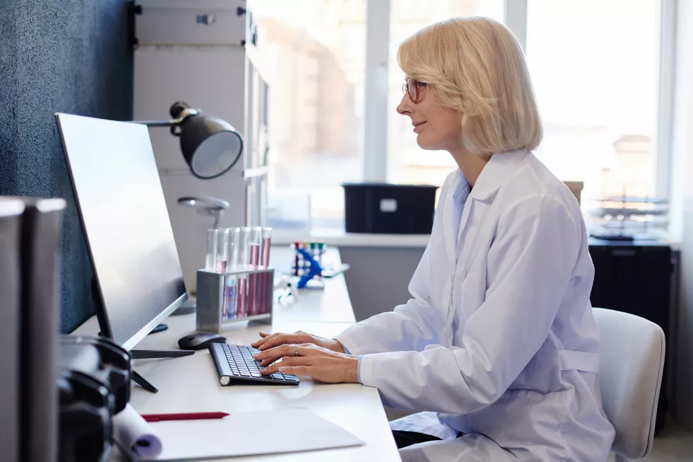 female-lab-chemist-using-computer-while-studying-chemicals-pharmaceutical-laboratory