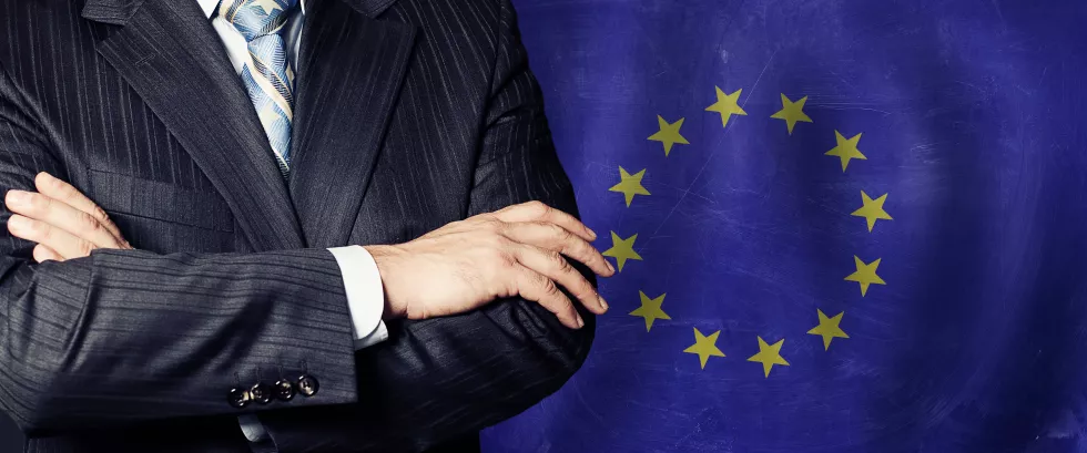 businessman-suit-with-his-hands-arms-crossed-flag-background