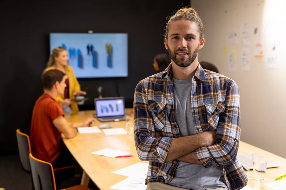 portrait-happy-caucasian-casual-businessman-with-hair-bun-smiling-meeting-room-casual-office-business-work-unaltered