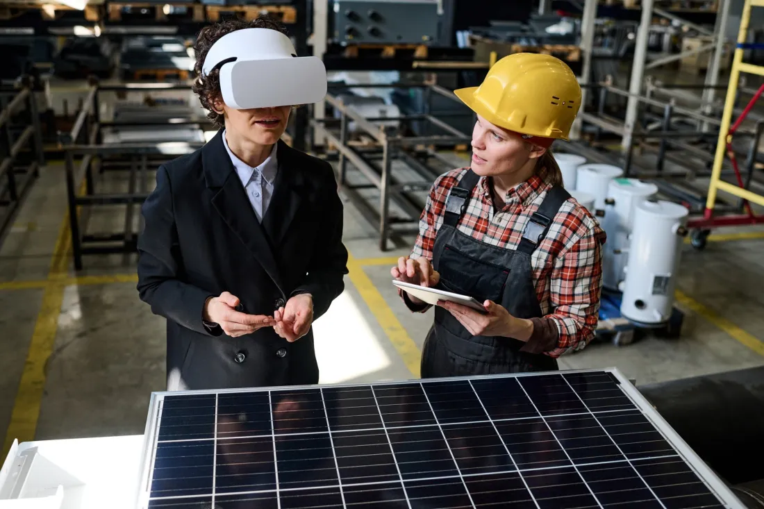 Two young engineers with a VR headset and a tablet next to a solar panel
