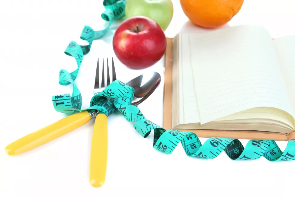 cutlery-tied-with-measuring-tape-book-with-fruit-isolated-white