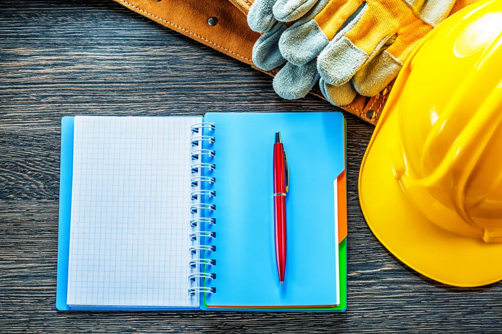 notepad-pen-tool-belt-protective-gloves-building-helmet-wooden-board