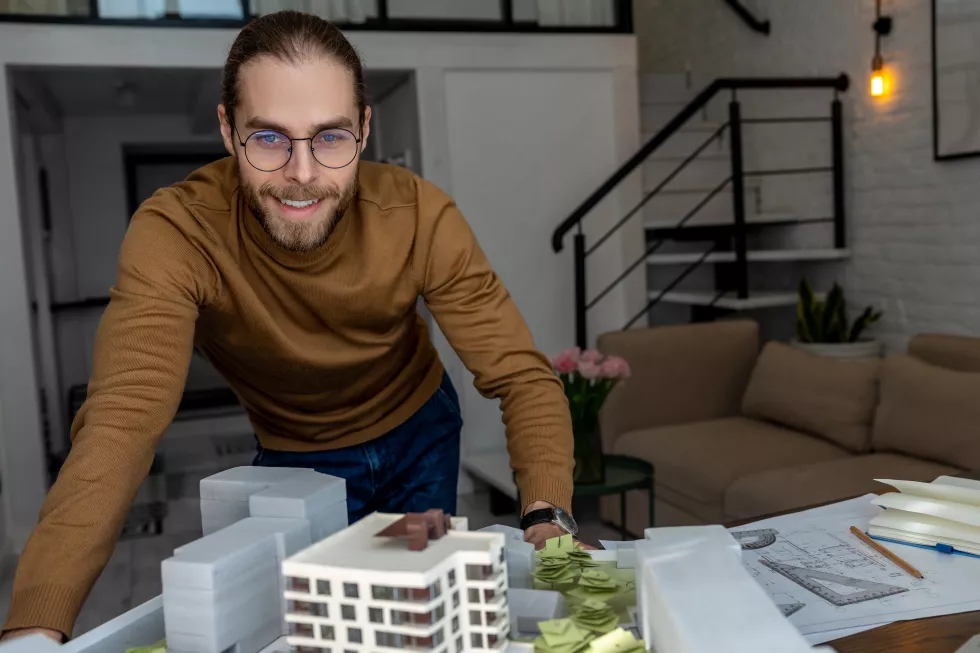 delighted-man-architect-glasses-working-office-with-creation-new-residential-complex-designing-layout-buildings