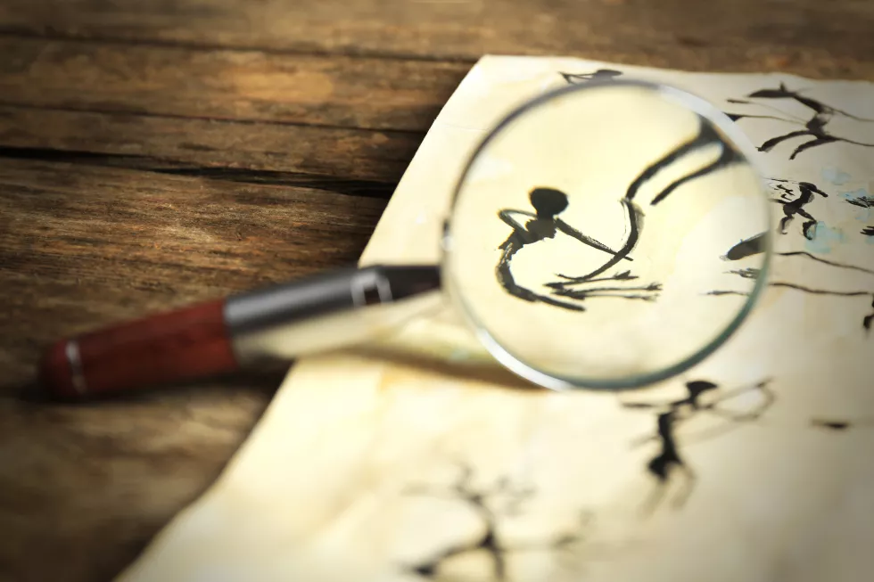 rock-paintings-with-magnifier-paper-wooden-table-close-up
