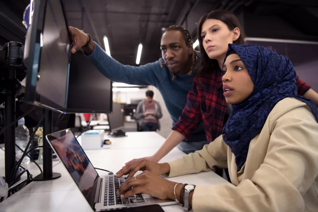 An international team of software developers working together at a laptop