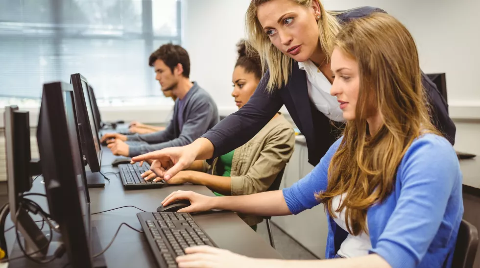 attractive-teacher-helping-her-student-computer-class
